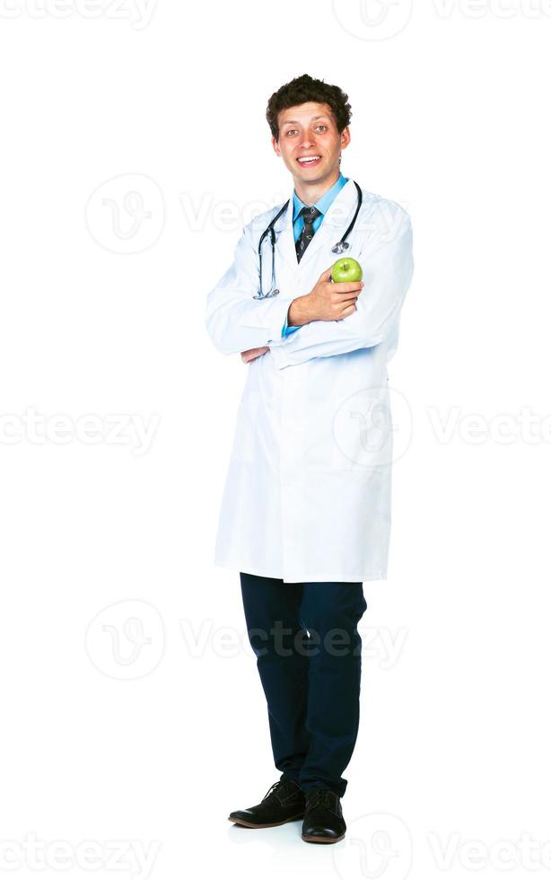 portrait de une souriant Masculin médecin en portant vert Pomme sur blanc Contexte photo