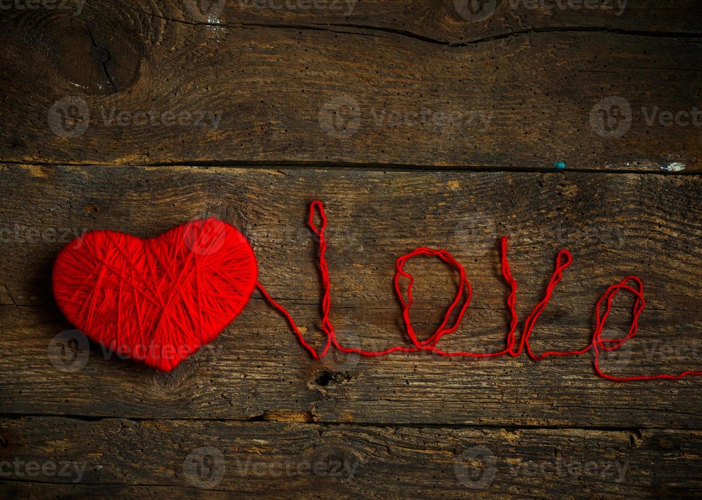 rouge cœur forme avec un une inscription l'amour fabriqué de la laine sur vieux minable en bois Contexte photo