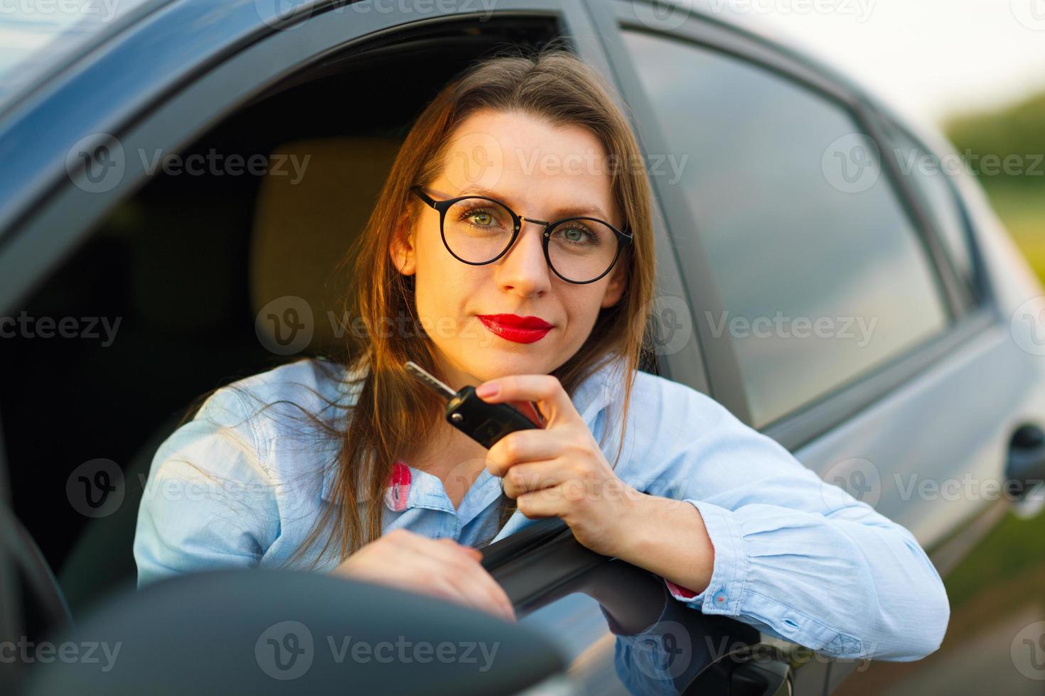 Jeune jolie femme séance dans une voiture avec le clés dans main photo