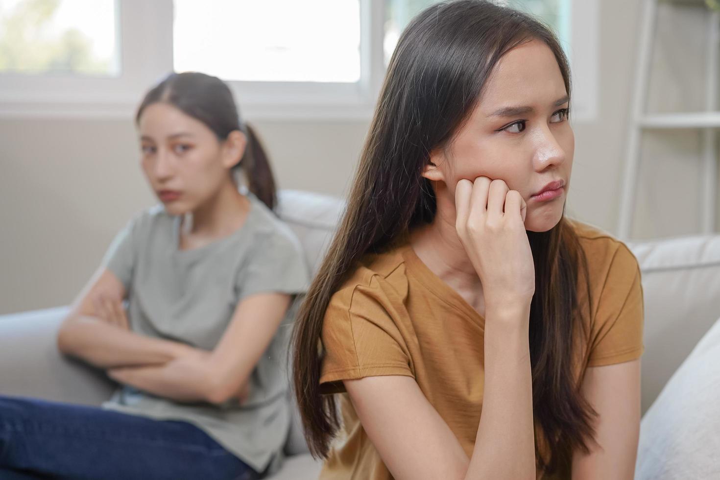 malheureux lesbienne, lgbt asiatique Jeune deux femmes, fille gay, couple l'amour bats toi sur canapé, relation est dans inquiéter. différent gens sont en colère et utilisation émotions à chaque autre, expression de déceptions. photo