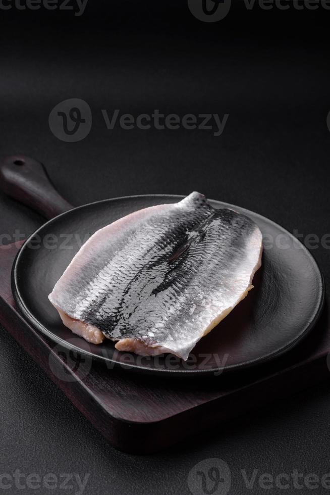 délicieux salé hareng filet dans pétrole sur une noir céramique assiette photo