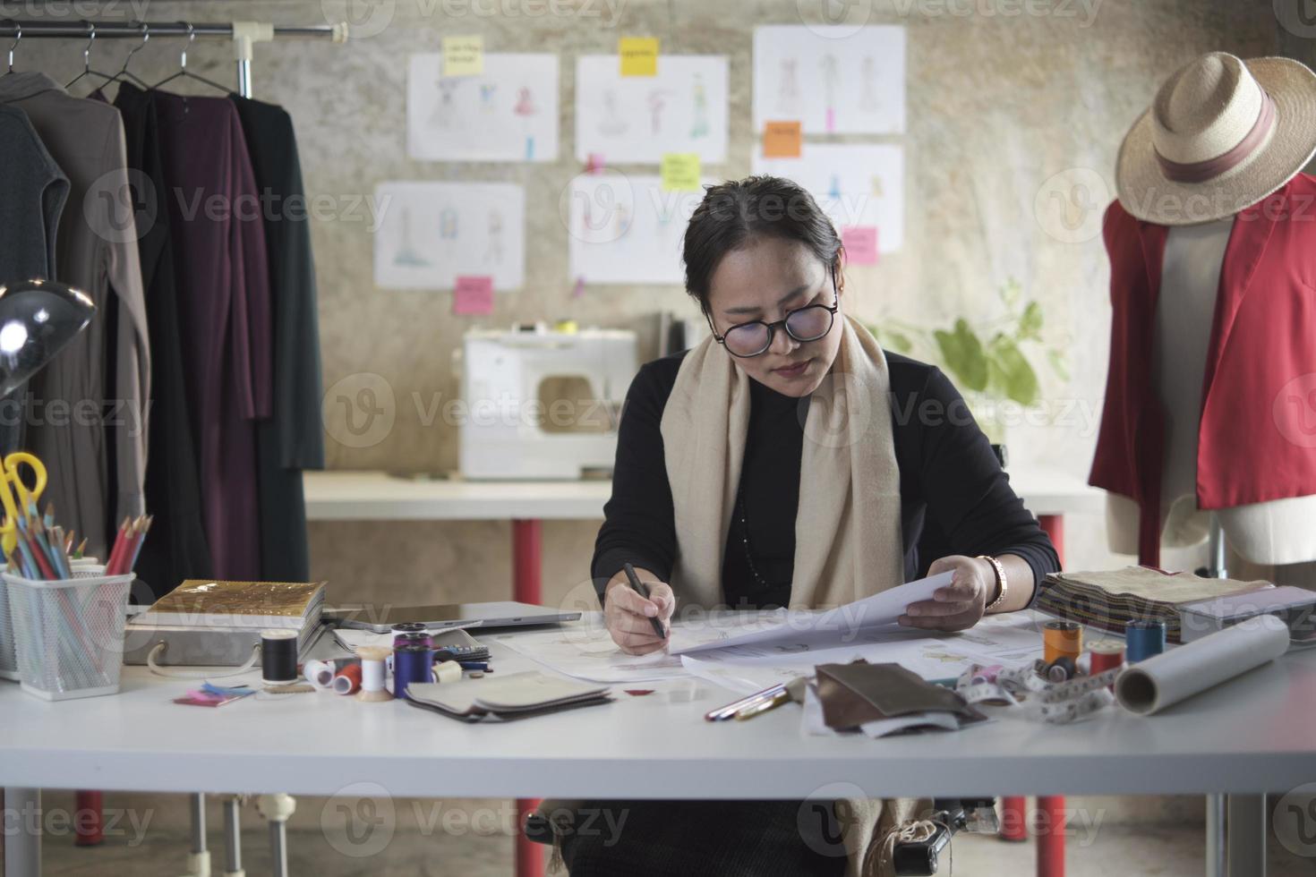 créatrice de mode asiatique d'âge moyen travaillant dans un studio par idée dessinant des croquis avec du fil coloré et cousant pour une collection de conception de robe, boutique professionnelle tailleur PME entrepreneur. photo