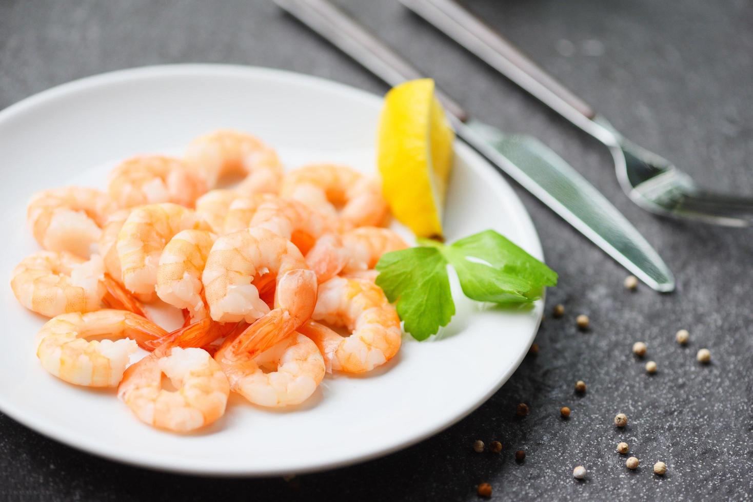 crevettes servi sur assiette avec citron, herbe, poivre sur blanc assiette - bouilli pelé crevette crevettes cuit dans le restaurant photo