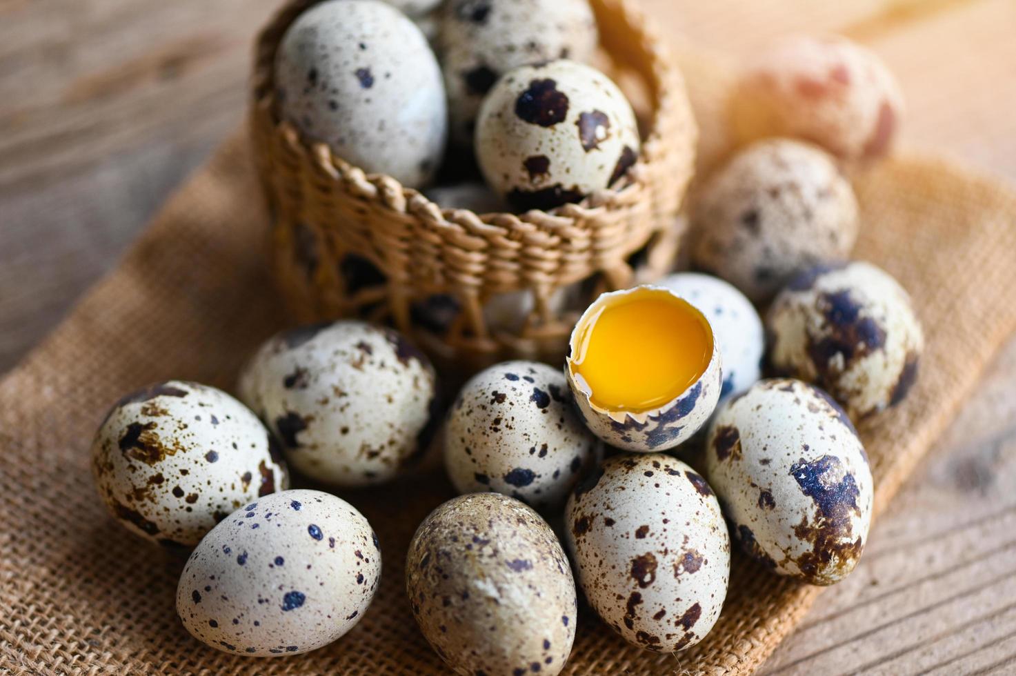 Caille des œufs sur panier, Frais Caille des œufs sur en bois table arrière-plan, brut des œufs avec peler Oeuf coquille photo