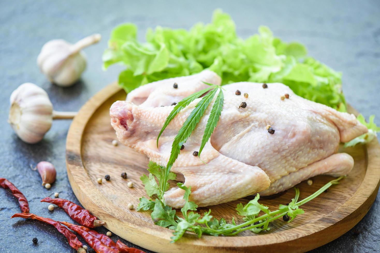 brut poulet avec marijuana feuille cannabis herbes et épices sur en bois plateau - Frais non cuit entier poulet Viande mariné avec Ingrédients pour cuisine photo