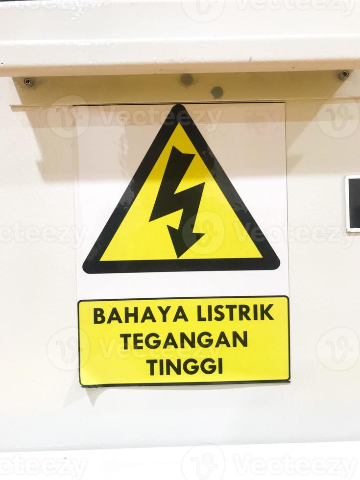 danger haute Tension signe avec texte isolé Jaune badge dans indonésien bahaya listerik tegangan tinggi photo