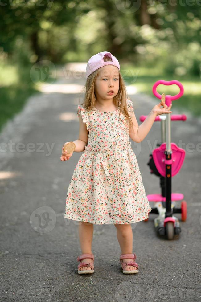 une peu fille 3 ans vieux dans une rose casquette monte une scooter. été  temps. 21178114 Photo de stock chez Vecteezy
