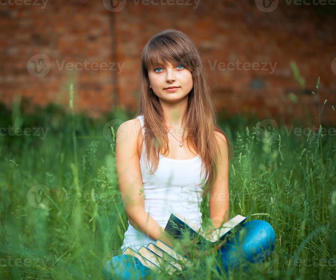 Jeune fille avec livre dans le parc sur vert herbe photo