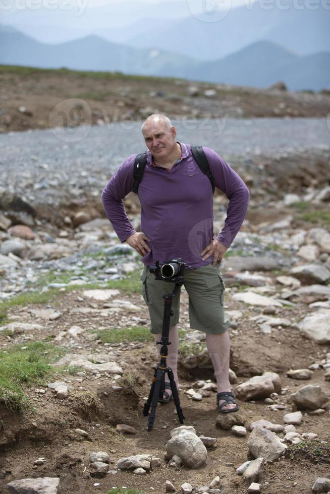 une homme est tournage une câble voiture dans le montagnes avec une vidéo caméra. une touristique écrit une Youtube Blog tandis que en voyageant. photo