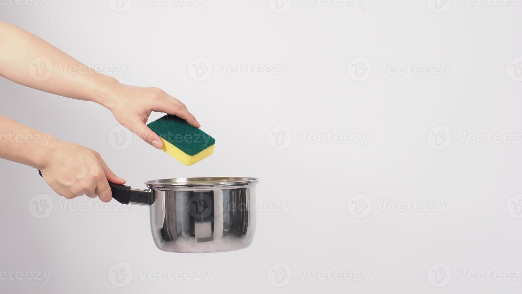 main d'homme de nettoyage de pot sur fond blanc nettoyant le pot antiadhésif avec une éponge à vaisselle pratique de couleur jaune sur le côté doux et verte sur le côté dur pour l'hygiène après la cuisson. marmite électrique photo