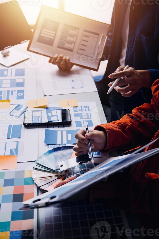 gros plan sur le développeur ux et le concepteur d'interface utilisateur remue-méninges sur la conception filaire de l'interface de l'application mobile sur la table avec le client breif et le code couleur au bureau moderne. agence de développement numérique créative photo