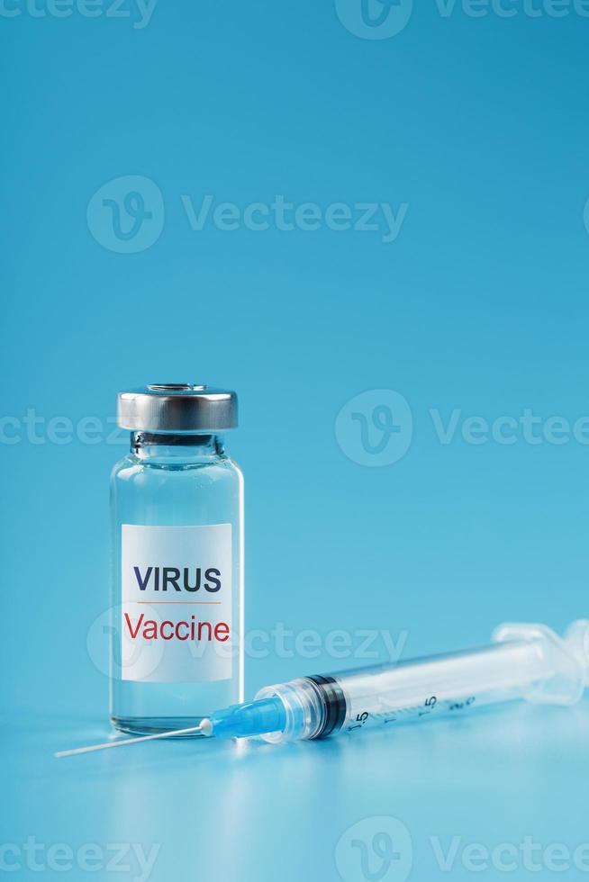 ampoule et seringue avec le vaccin contre le virus contre les maladies sur fond bleu. photo