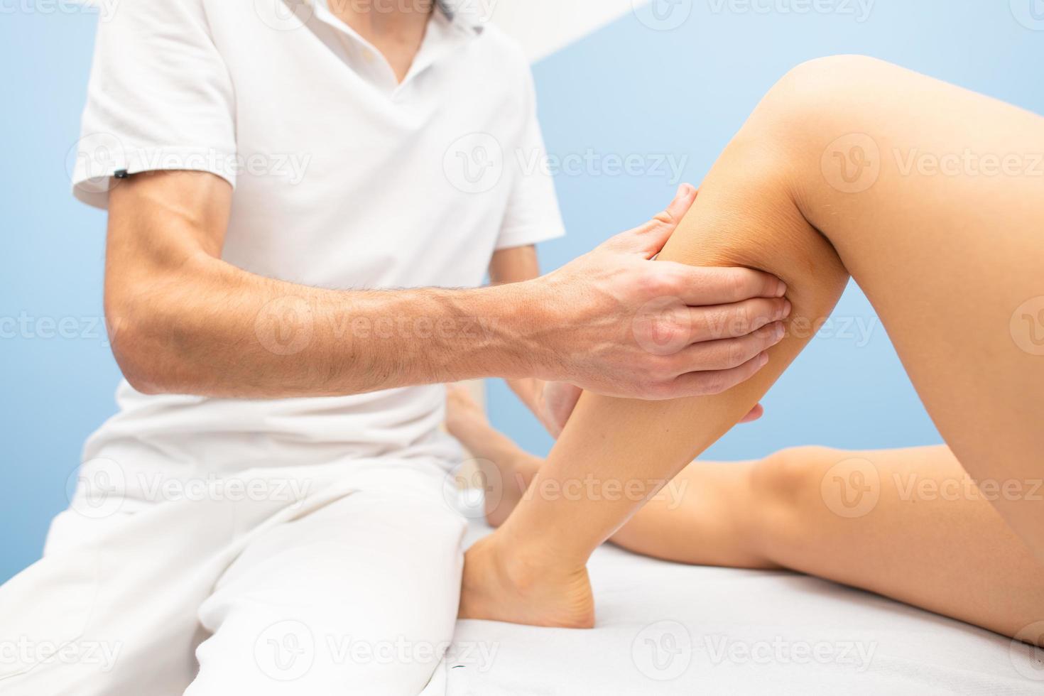 massage délicat des mollets dans l'atelier d'un physiothérapeute professionnel photo