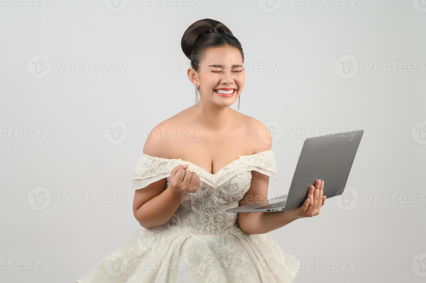 Jeune belle mariée asiatique pose avec un ordinateur portable à la main photo