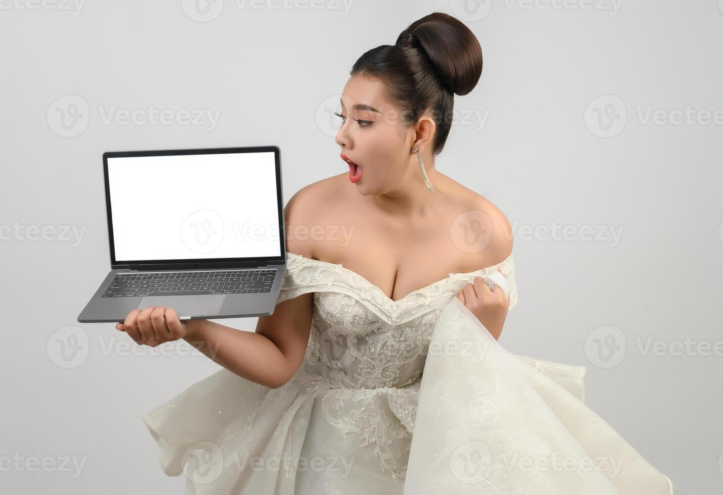 Jeune belle mariée asiatique pose avec un ordinateur portable maquette à la main photo