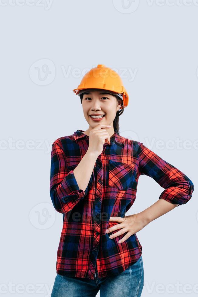 Jeune femelle ingénieur portant Jaune casque supporter avec charmant sourire posture photo