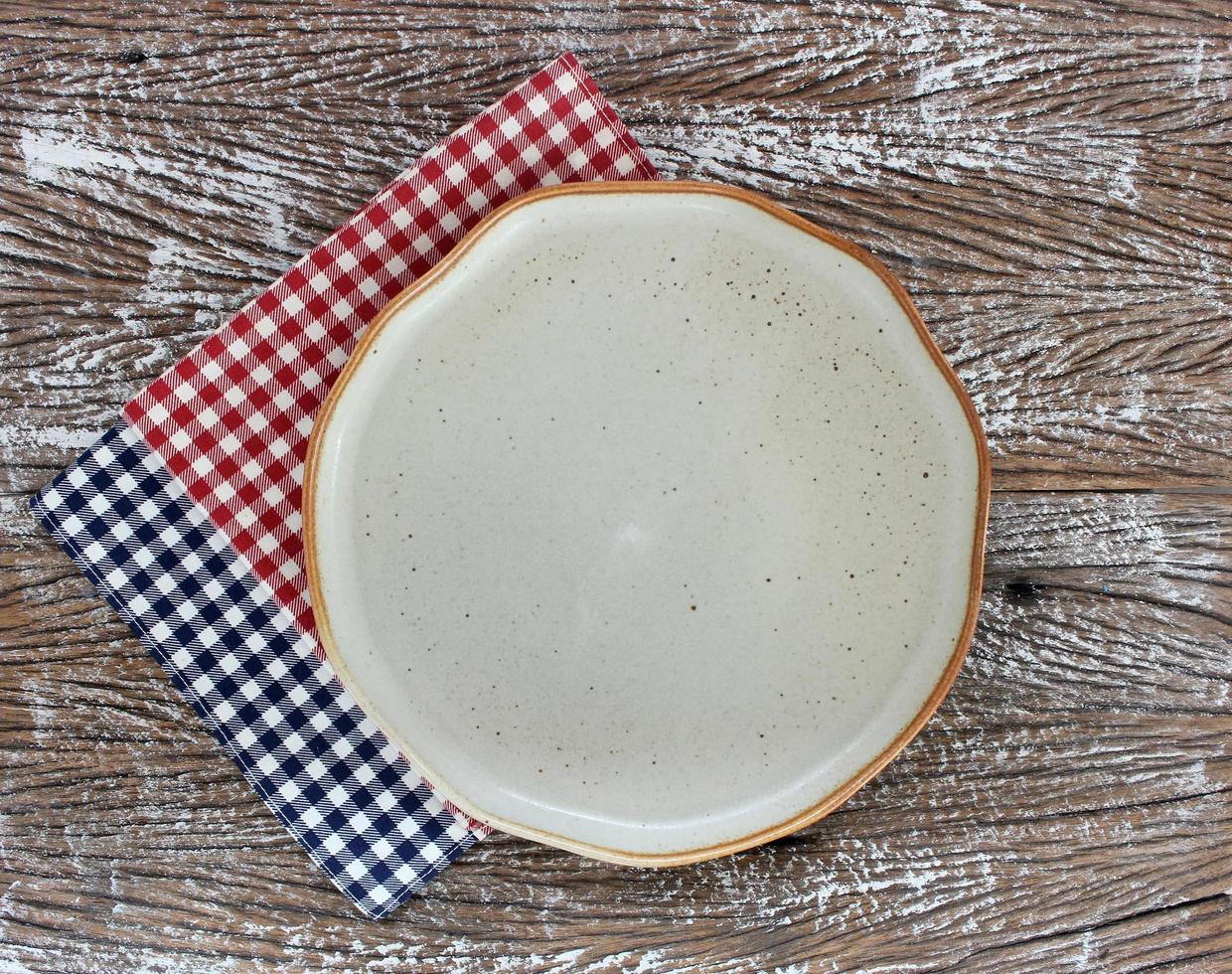 Vue de dessus d'une assiette en céramique vide avec des serviettes sur un fond de table en bois photo