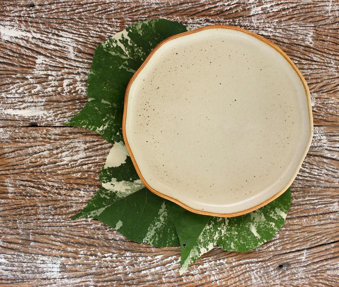 Vue de dessus d'une assiette en céramique vide avec des feuilles sur un fond de table en bois photo