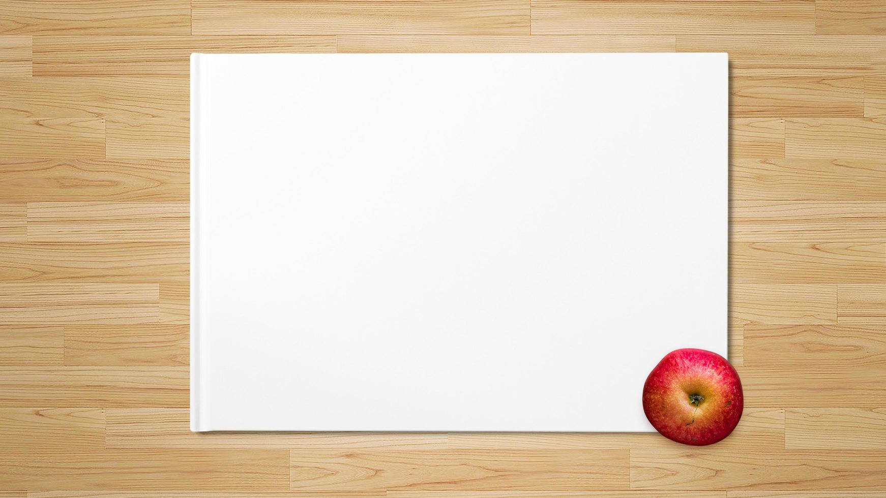 pomme rouge sur papier blanc sur fond de bois photo