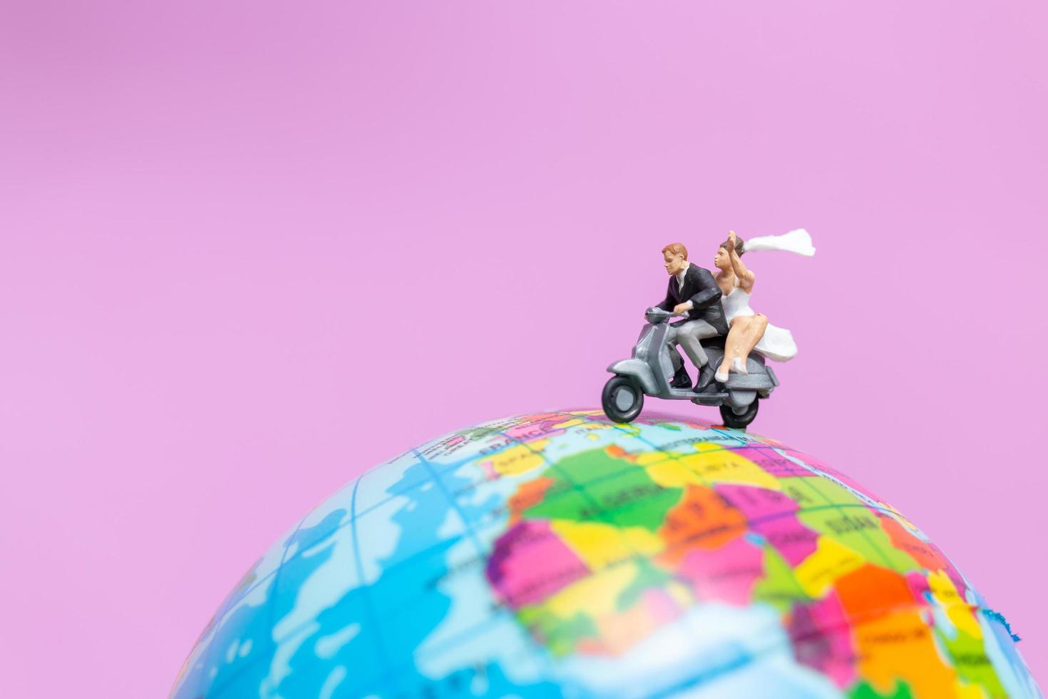 Couple miniature à moto sur un globe terrestre photo