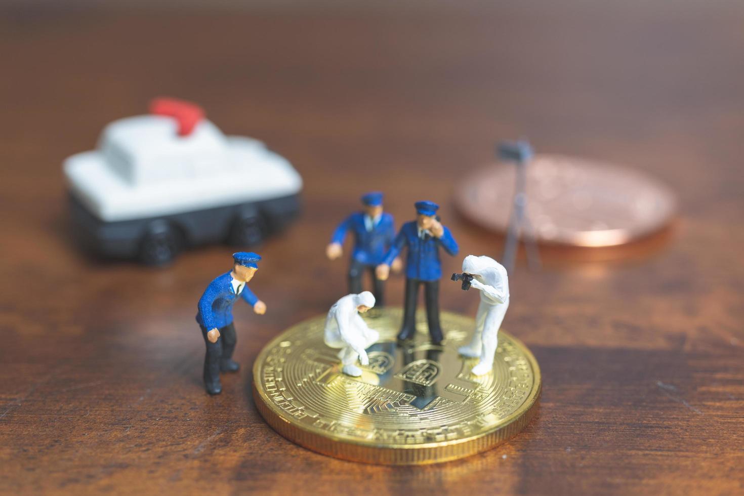 police miniature et détectives debout devant la crypto-monnaie bitcoin, concept de cybercriminalité photo
