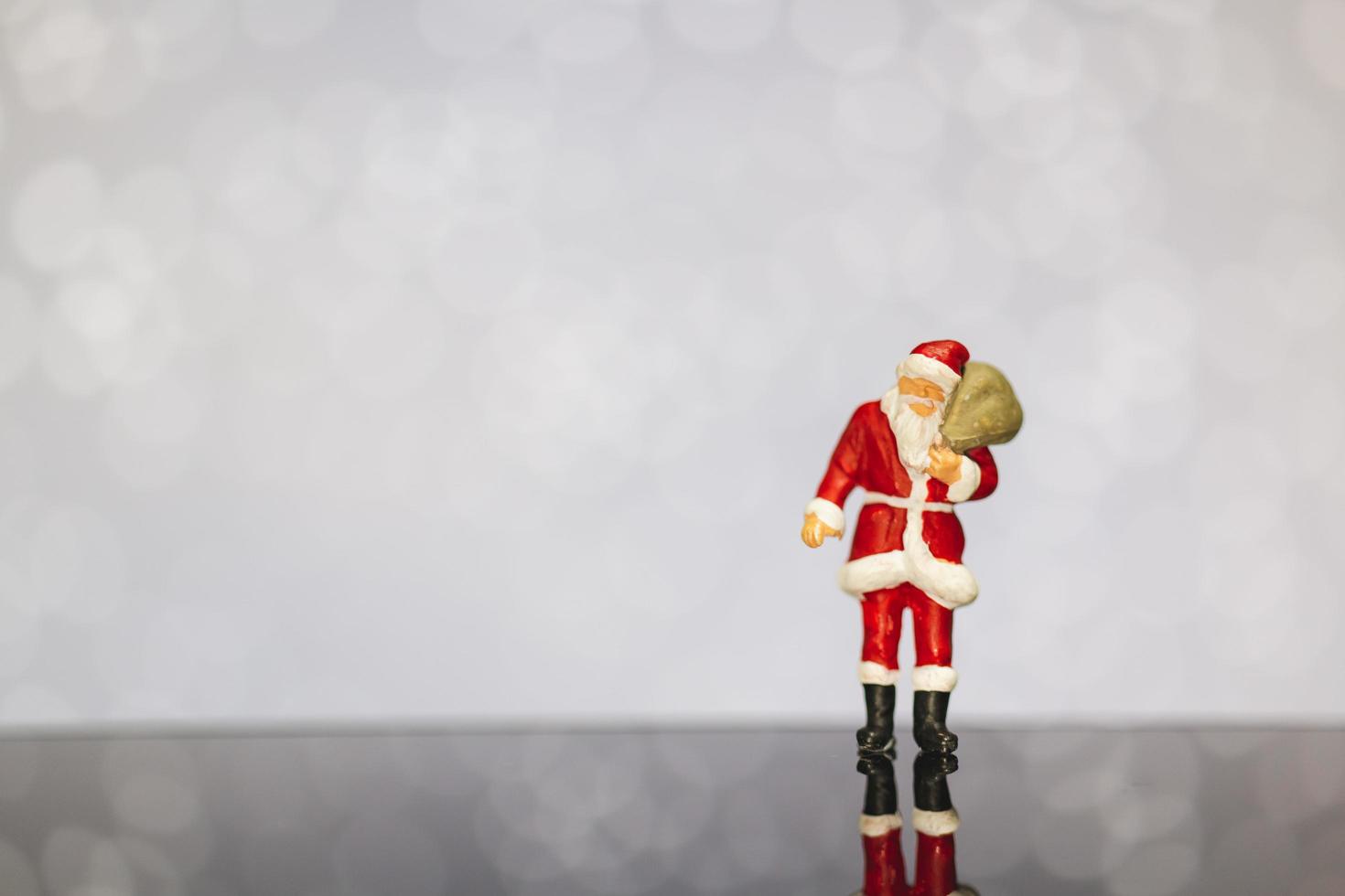 Père Noël miniature portant un sac sur un fond de bokeh, joyeux Noël et bonne année concept. photo