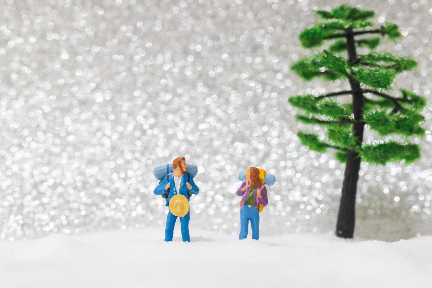 Backpackers miniatures marchant sur un fond de neige, concept d'hiver photo