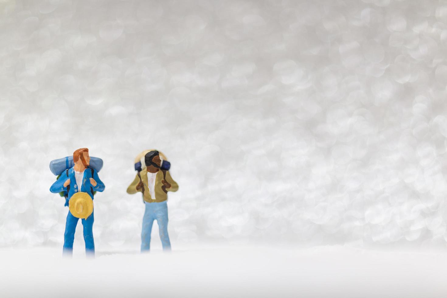 Backpackers miniatures marchant sur un fond de neige, concept d'hiver photo