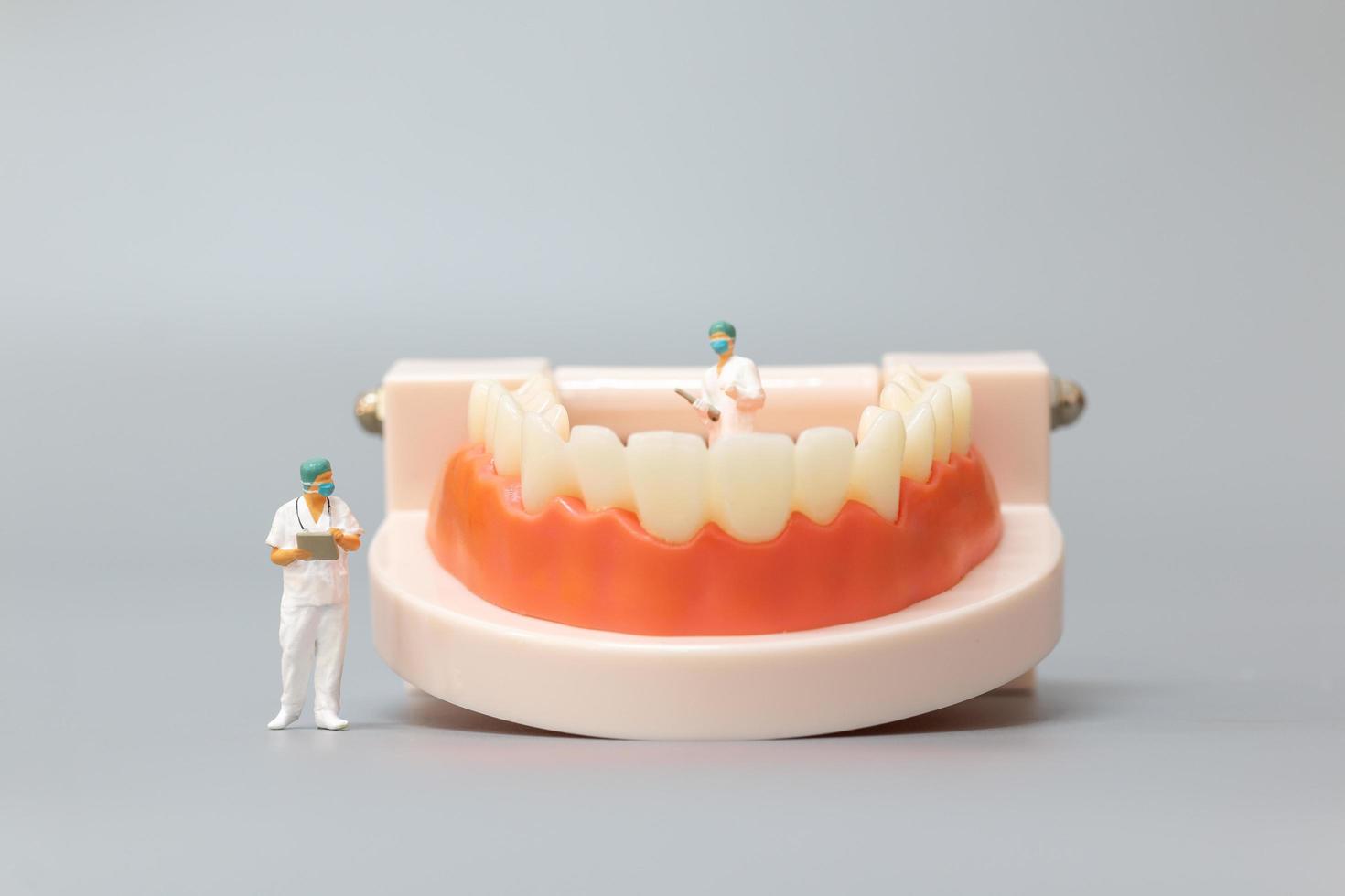 Dentiste miniature réparant les dents humaines avec les gencives et l'émail, la santé et le concept médical photo