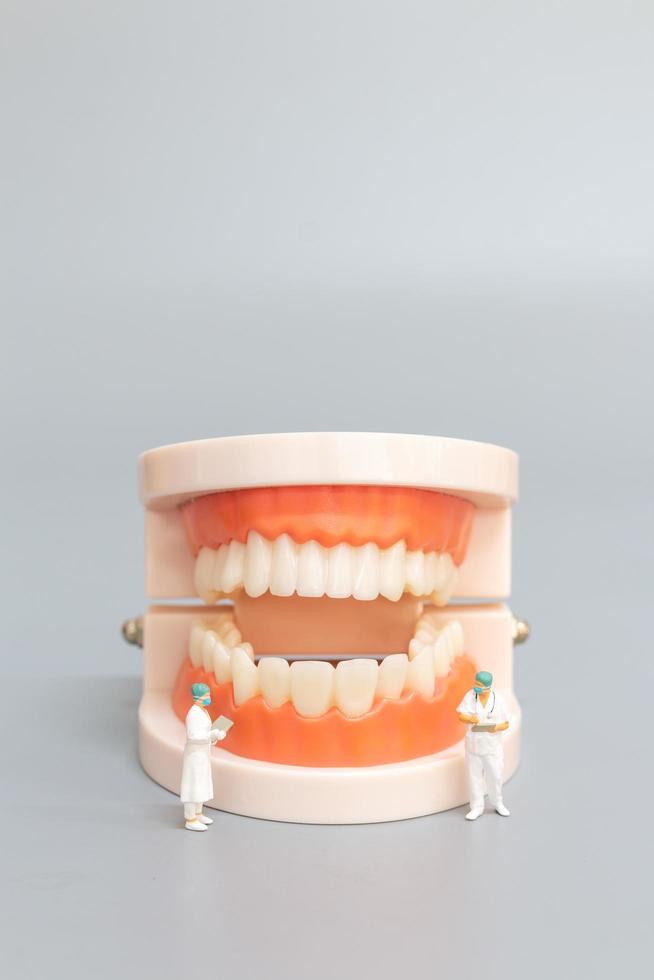 Dentiste miniature réparant les dents humaines avec les gencives et l'émail, la santé et le concept médical photo