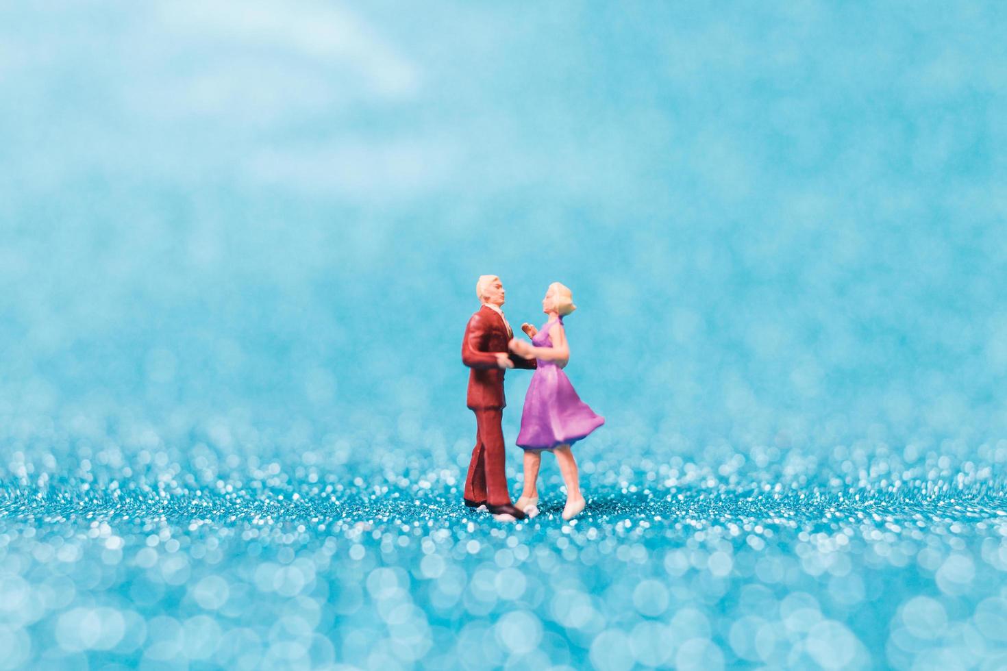 Couple miniature dansant sur fond de paillettes bleues, concept de la Saint-Valentin photo