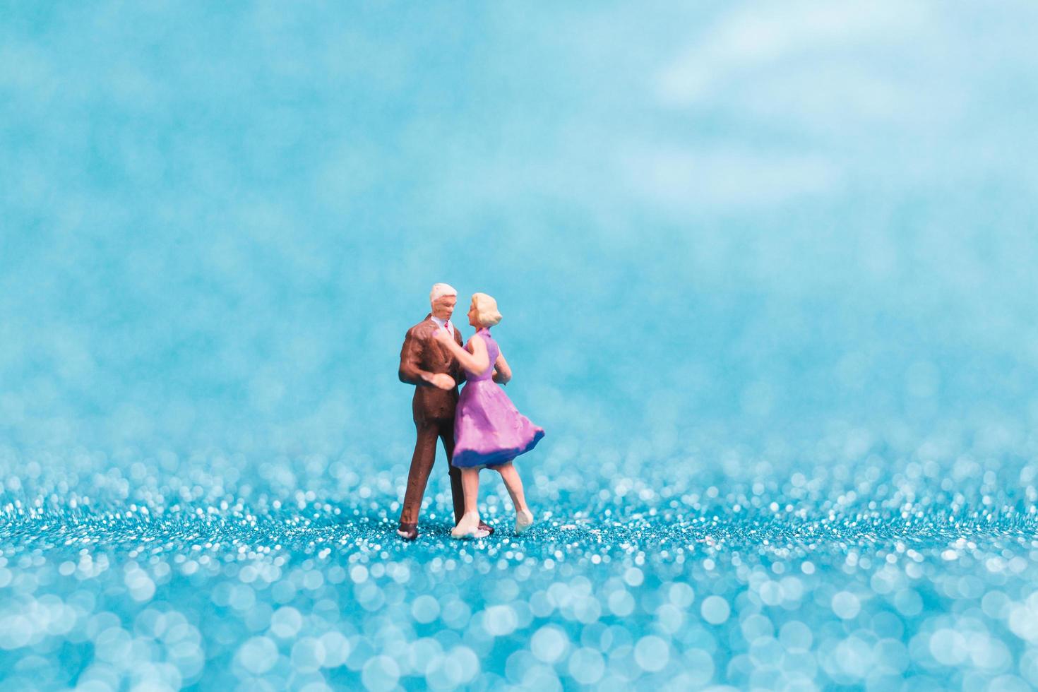 Couple miniature dansant sur fond de paillettes bleues, concept de la Saint-Valentin photo