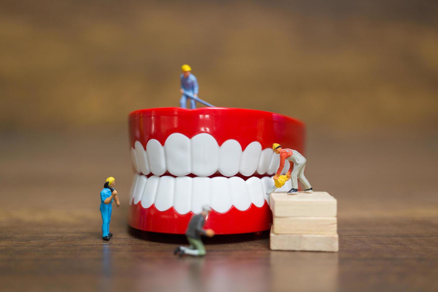 travailleurs miniatures réparant une dent, des soins de santé et un concept médical photo