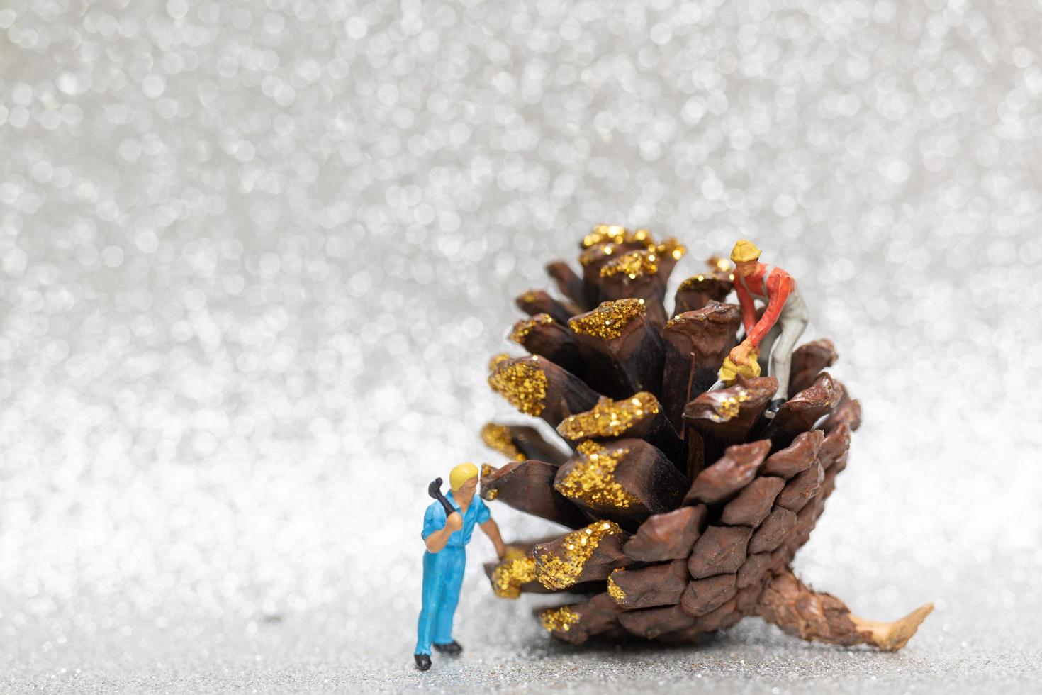 travailleurs miniatures faisant équipe pour préparer une pomme de pin de Noël, Noël et bonne année concept photo