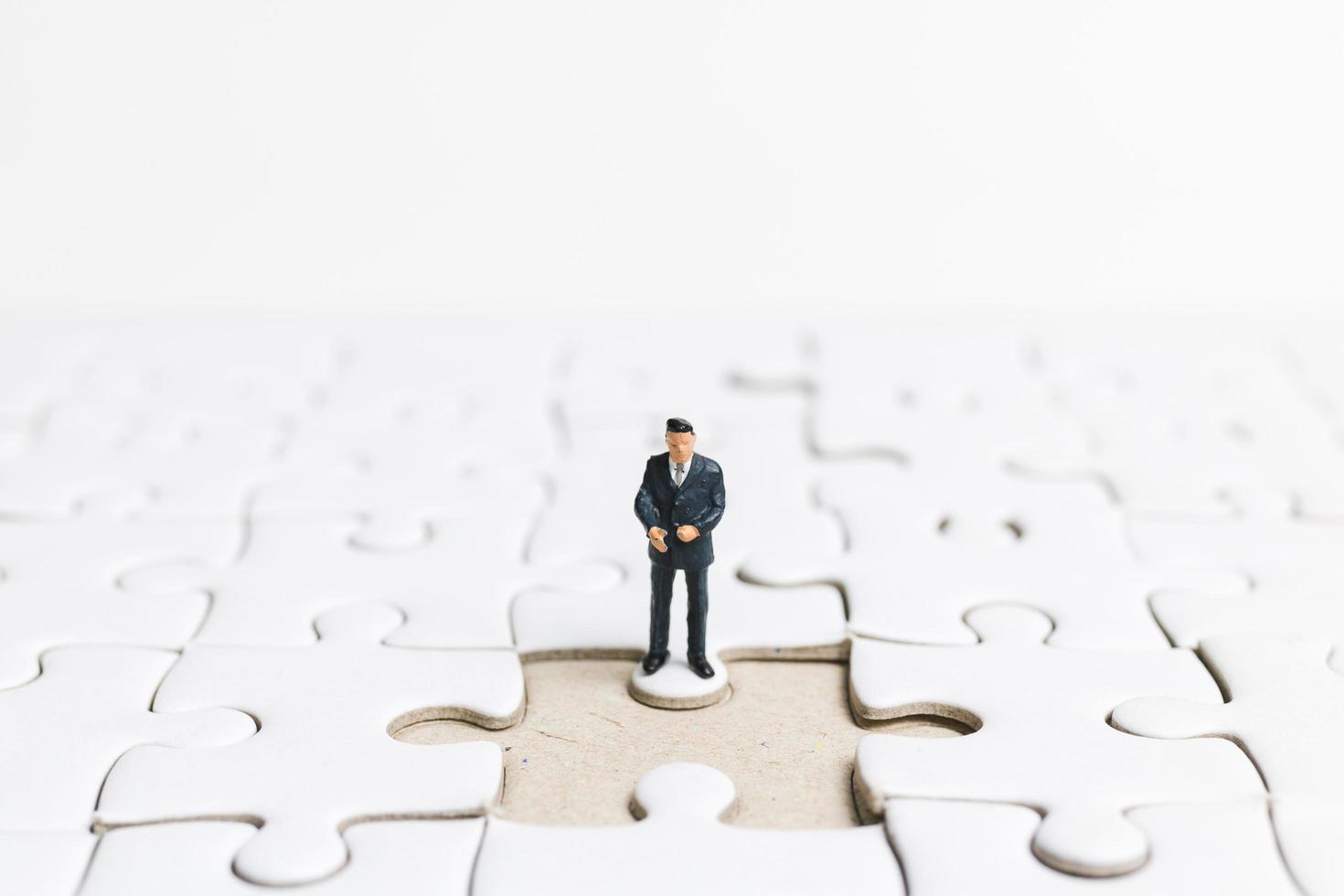 homme d & # 39; affaires miniature debout sur un puzzle blanc, concept d & # 39; entreprise photo