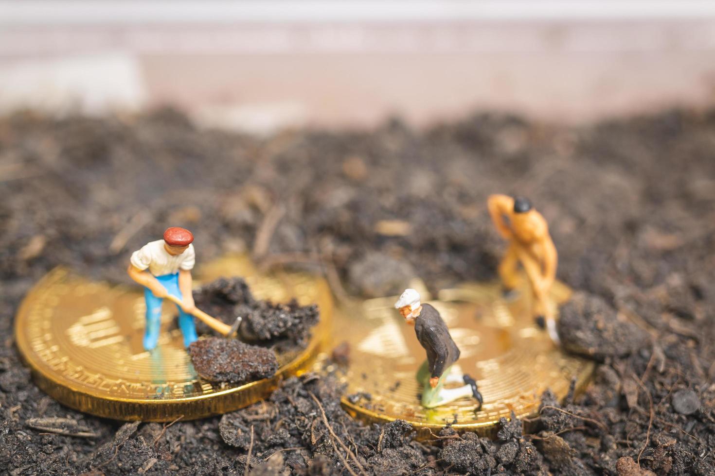 travailleurs miniatures creusant le sol pour découvrir la crypto-monnaie bitcoin brillante, concept de travail réussi photo