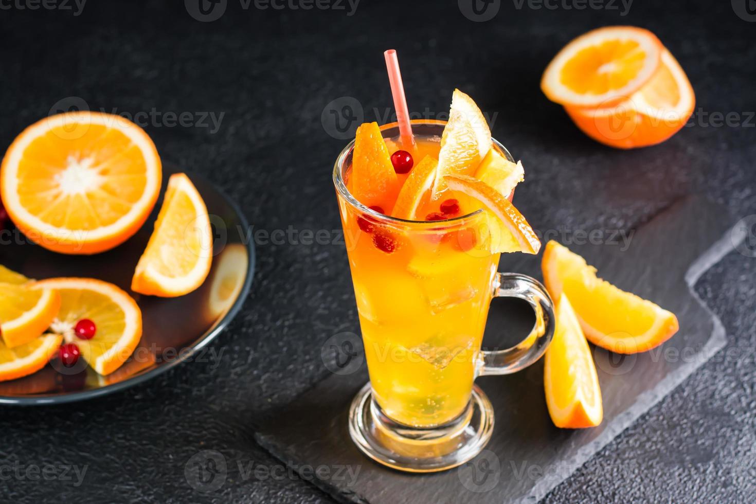 Orange canneberge pétillant cocktail dans une verre et des fruits et baies proche sur une ardoise sur une foncé Contexte. fait maison mocktail photo