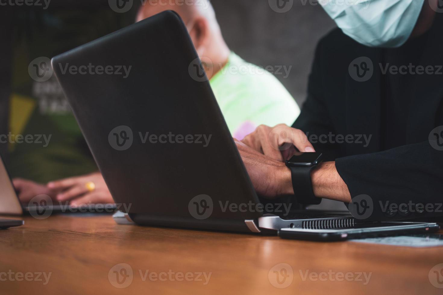 deux personnes parlant au bureau et travaillant sur des ordinateurs portables photo