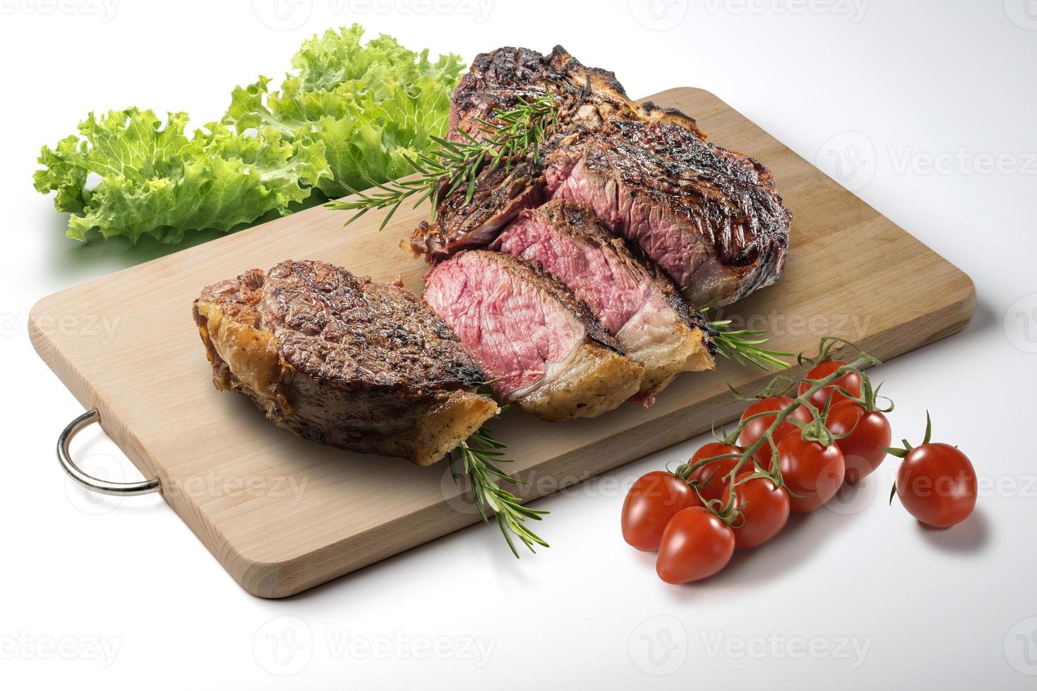 Fiorentina t-bone steak coupé sur planche à découper en bois rectangulaire et légumes photo
