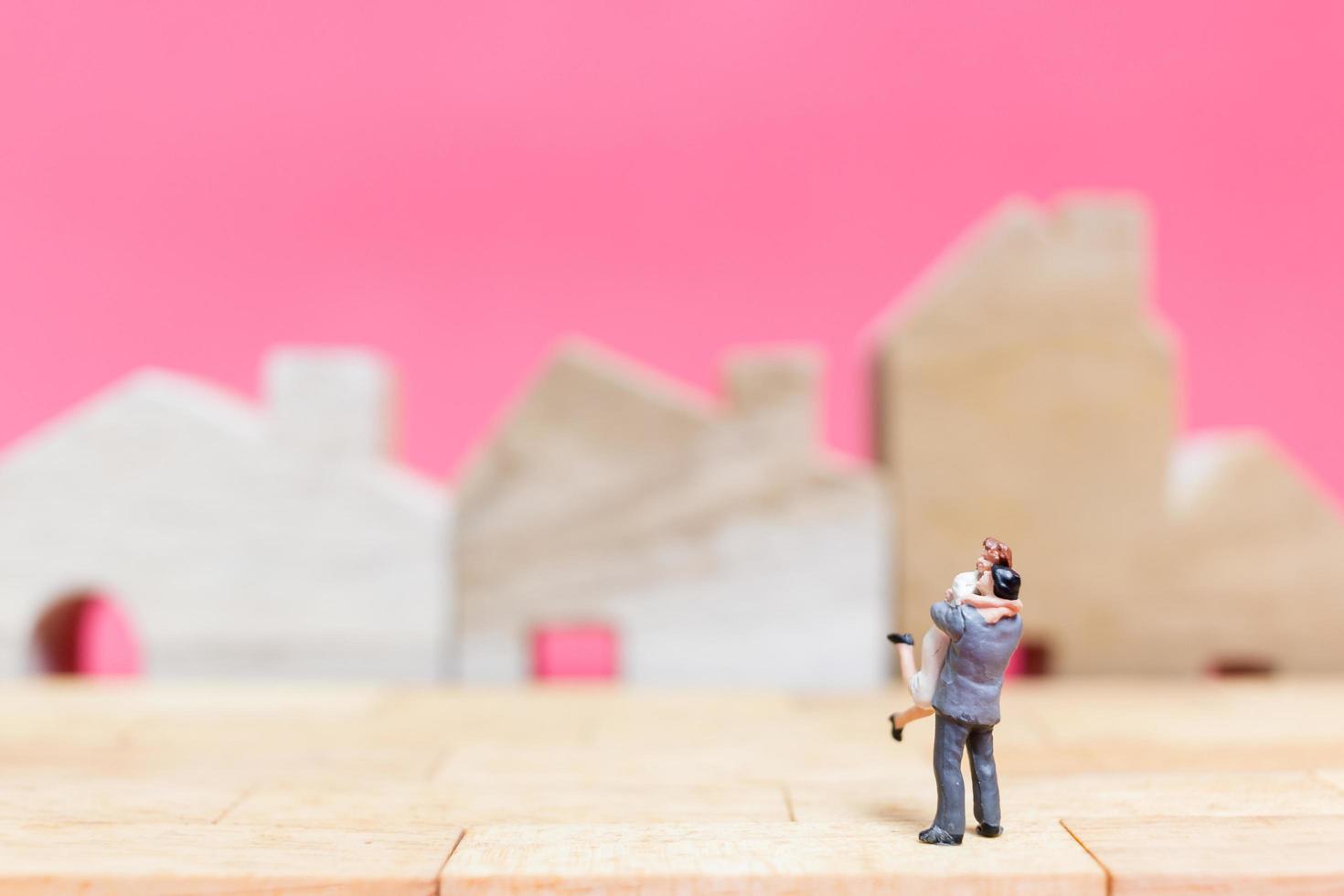 Couple miniature avec des maisons sur fond rose, concept de la Saint-Valentin photo