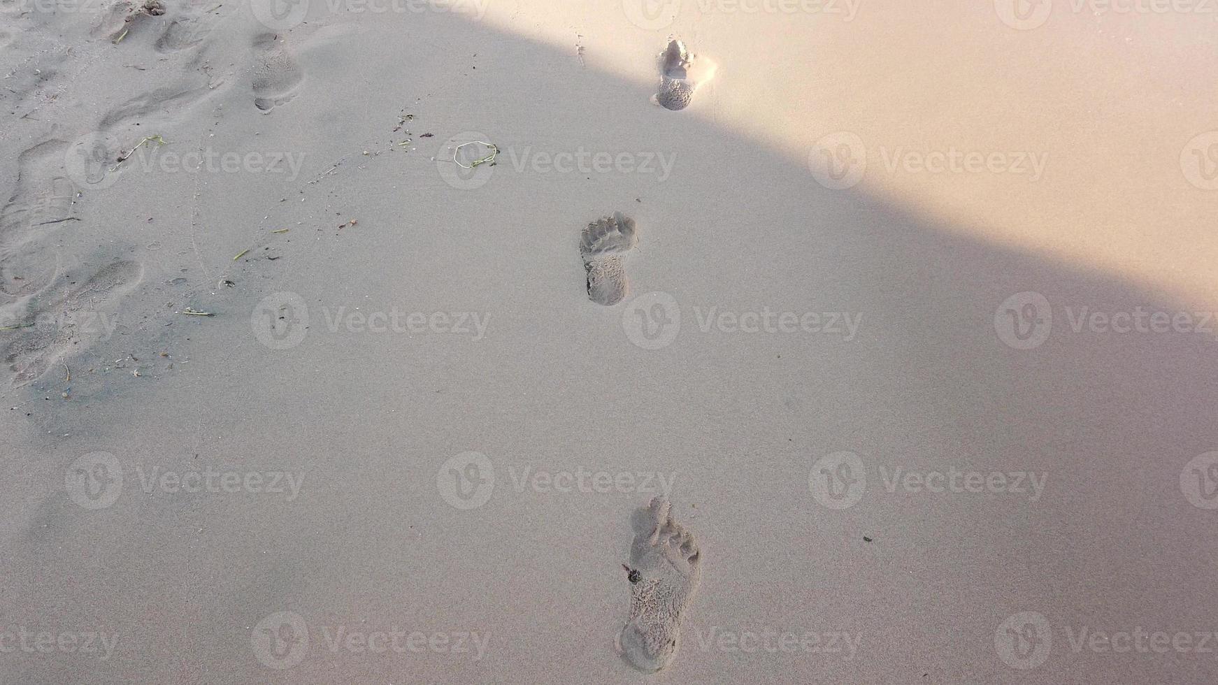 fermer de Humain empreintes dans le humide le sable à le bord de mer. paix de le mouvement de mer l'eau ou vagues. photo