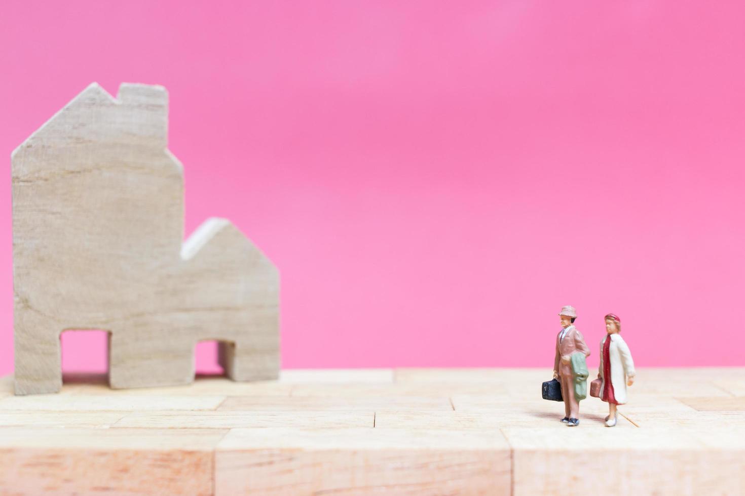 Couple miniature avec des maisons sur fond rose, concept de la Saint-Valentin photo