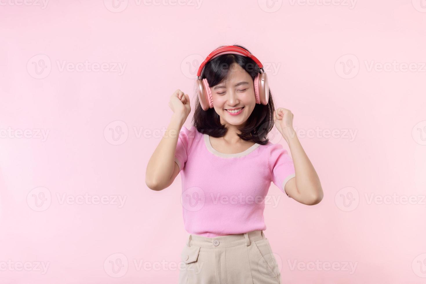 sourire jolie modèle la personne Ecoutez la musique chanson et prendre plaisir Danse avec sans fil casque de musique en ligne l'audio radio son. positif amusement sorti joyeux jeunesse femelle femme chanter sur rose isolé Contexte studio photo