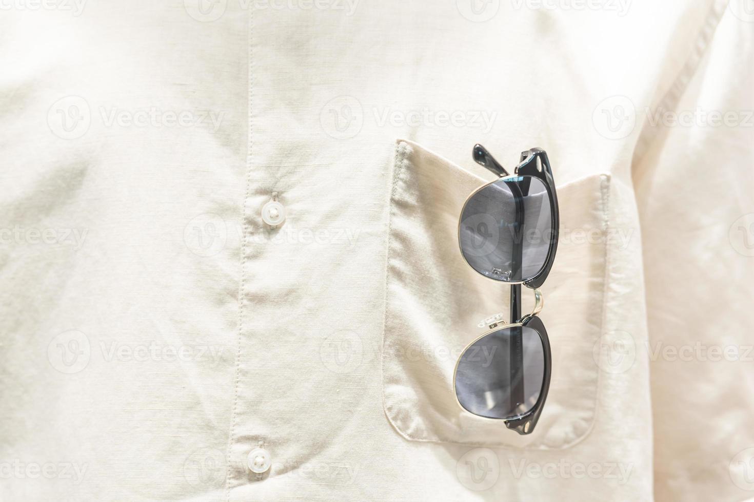 des lunettes de soleil dans chemise poche. mettre des lunettes de soleil dans poche, Aller sur vacances. chemise poche avec Soleil lunettes. photo