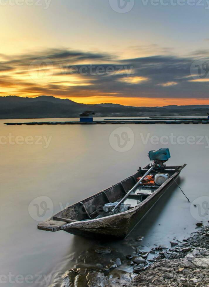 un bateau au bord d'un lac au beau coucher de soleil photo