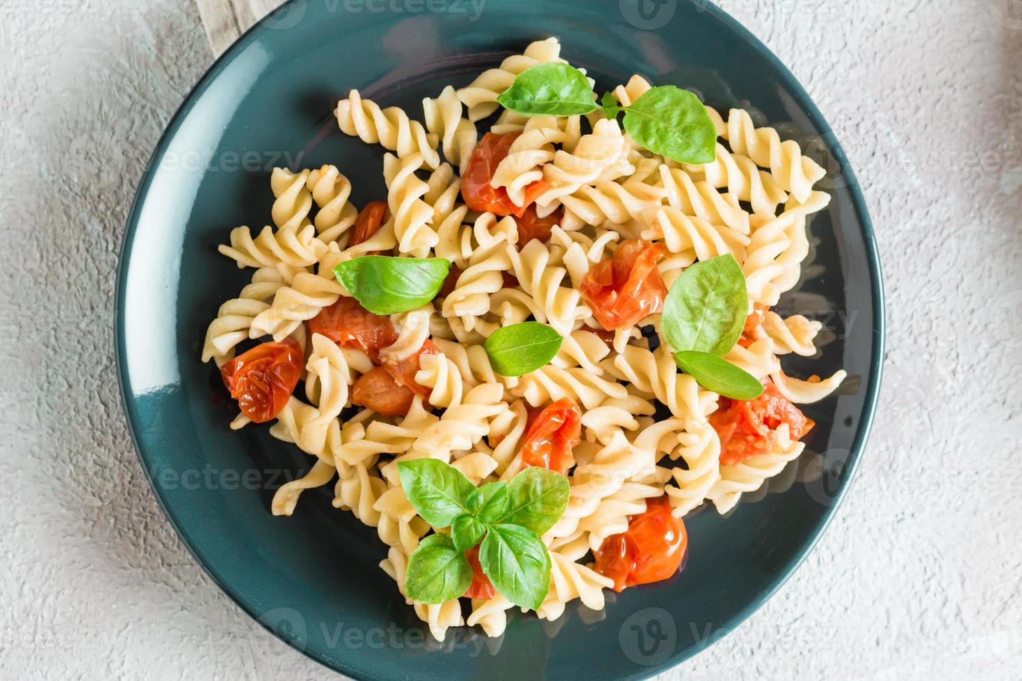 prêt à manger Pâtes avec tomates et basilic sur une assiette et Ingrédients sur le tableau. méditerranéen cuisine. fermer. Haut vue photo