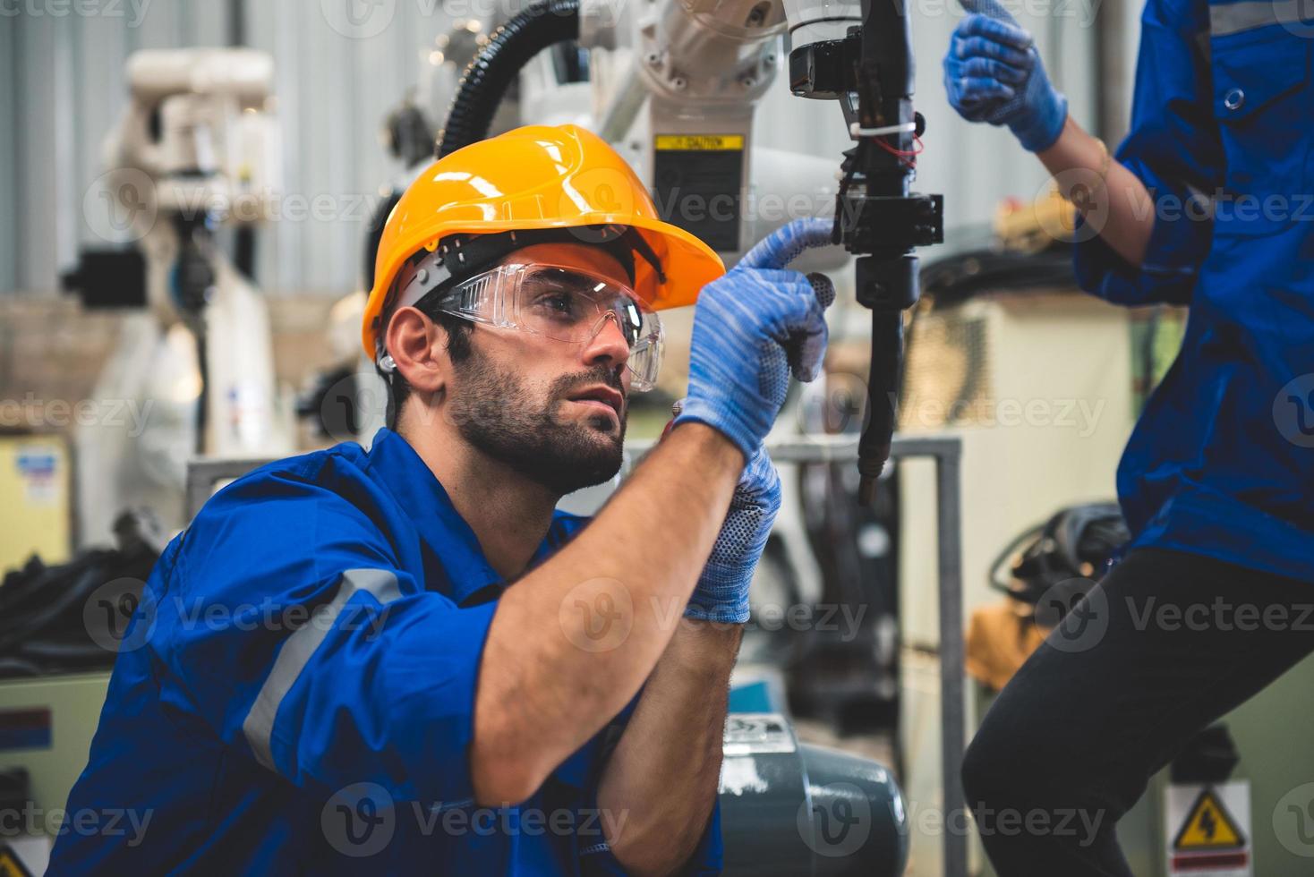 ingénieurs mécanicien en utilisant ordinateur manette robotique bras pour soudage acier dans acier usine atelier. industrie robot programmation Logiciel pour automatique fabrication La technologie photo