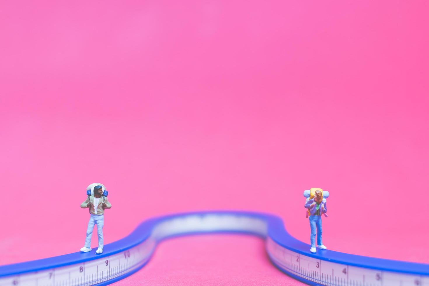 Couple miniature de voyageurs sur un pont avec un fond rose photo