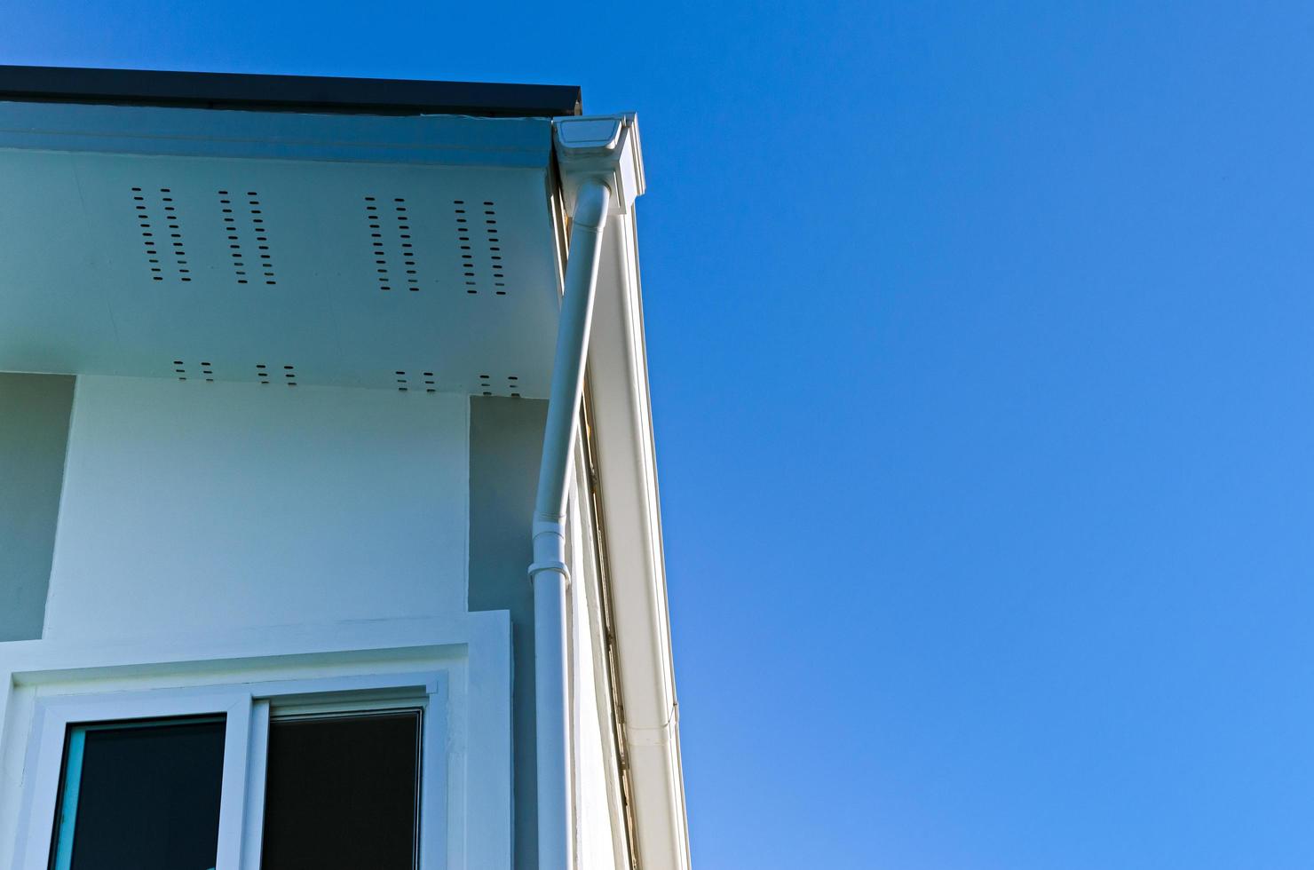 maison toit avec pluie gouttière de toit Haut maison et grand les fenêtres sur bleu ciel arrière-plan, Nouveau moderne bâtiment photo