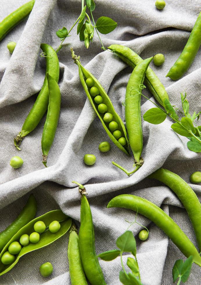 Gousses de pois verts avec des feuilles de pois sur un fond de tissu photo